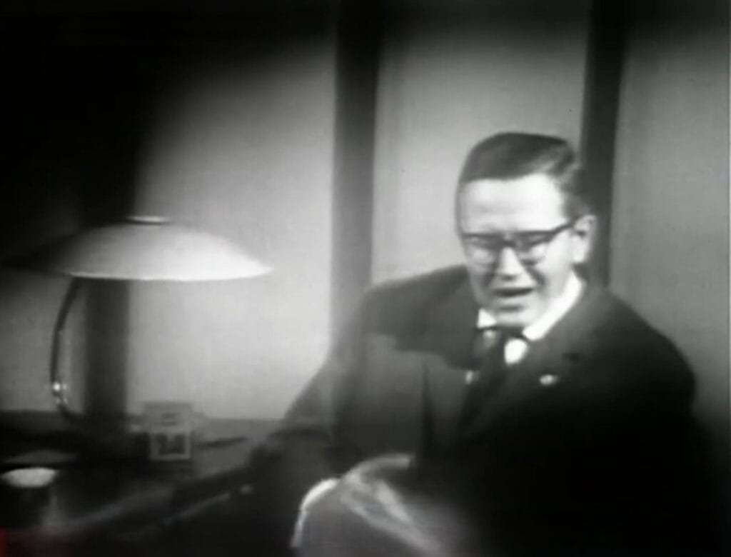 Presentador de televisión Karl-Eduard von Schnitzler sentado frente a un escritorio con lámpara durante una emisión de Der Schwarze Kanal.