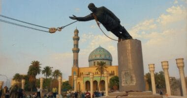 Pintura al óleo que recrea el derribo de la estatua de Sadam Husein mediante grúas en la plaza Firdos de Bagdad con mezquita detrás.