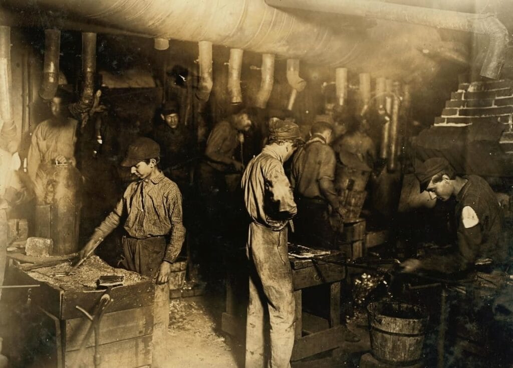 Fotografía de época en sepia con niños obreros trabajando entre maquinaria en una fábrica oscura, contexto de La Internacional.