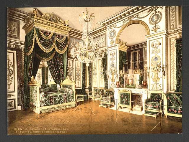 Oulenta habitación imperial de Napoleón en Fontainebleau con detalles dorados y simbología neoclásica de poder.