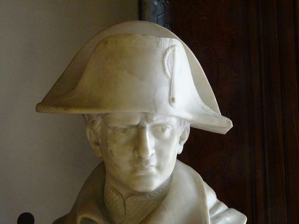 Busto neoclásico en mármol blanco de Napoleón Bonaparte con su emblemático sombrero bicorne y mirada firme.