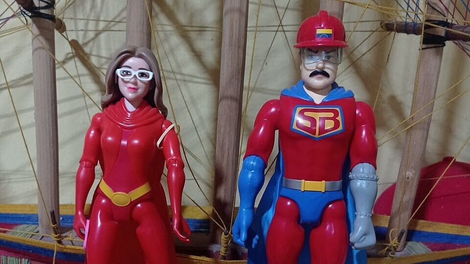 Dos figuras de acción de plástico de Súper Bigote y su compañera sobre el fondo de un barco artesanal.