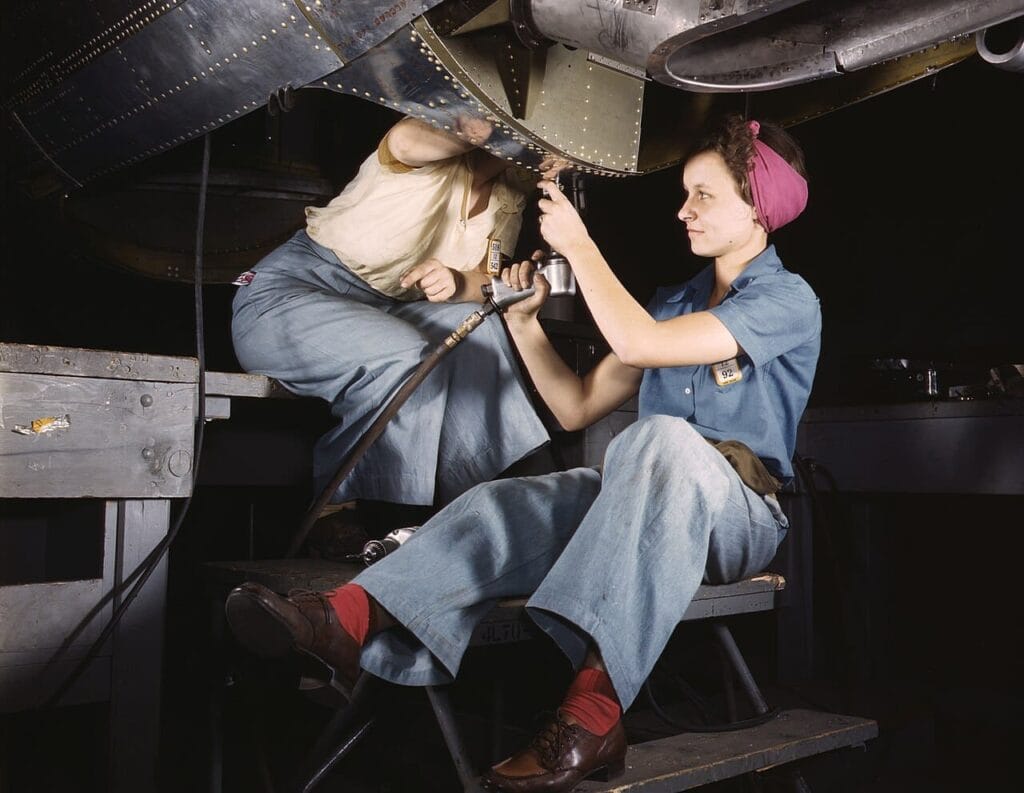 Dos mujeres ensamblando la estructura de un avión militar con remachadora neumática en Douglas Aircraft en 1942.