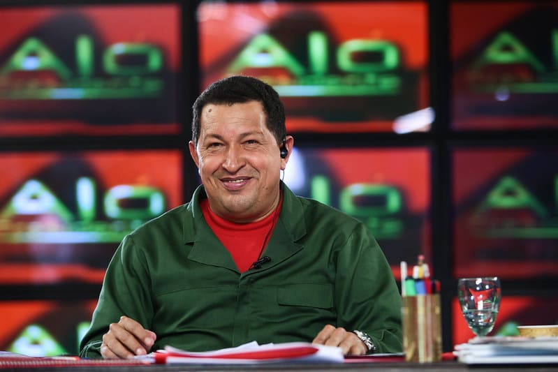 Muestra de propaganda chavista con Hugo Chávez sonriendo en el set de Aló Presidente vistiendo camisa verde militar.
