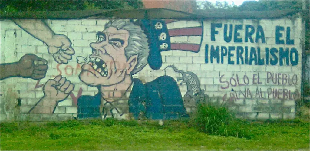 Ejemplo de propaganda chavista en mural urbano caricaturizando al Tío Sam siendo golpeado por puños con consignas políticas.