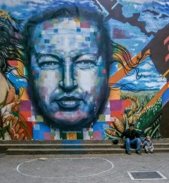 Mural de propaganda chavista con el rostro de Hugo Chávez al centro entre figuras indígenas y maizales.