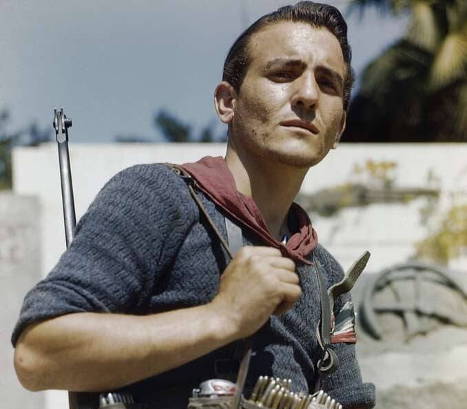 Joven partisano italiano a color con fusil, canana con munición y pañuelo rojo al cuello en Florencia durante la liberación de 1944.